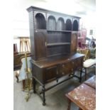 1930'S OAK PURITAN STYLE DRESSER WITH TWIN CUPBOARD DELFT RACK AND CENTRAL BANK OF TWO DRAWERS ON