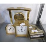 A SATIN BRASS AND GLASS ARCH SHAPED BATTERY ALARM CLOCK A SMALL MILESTONE SHAPED SATIN BRASS
