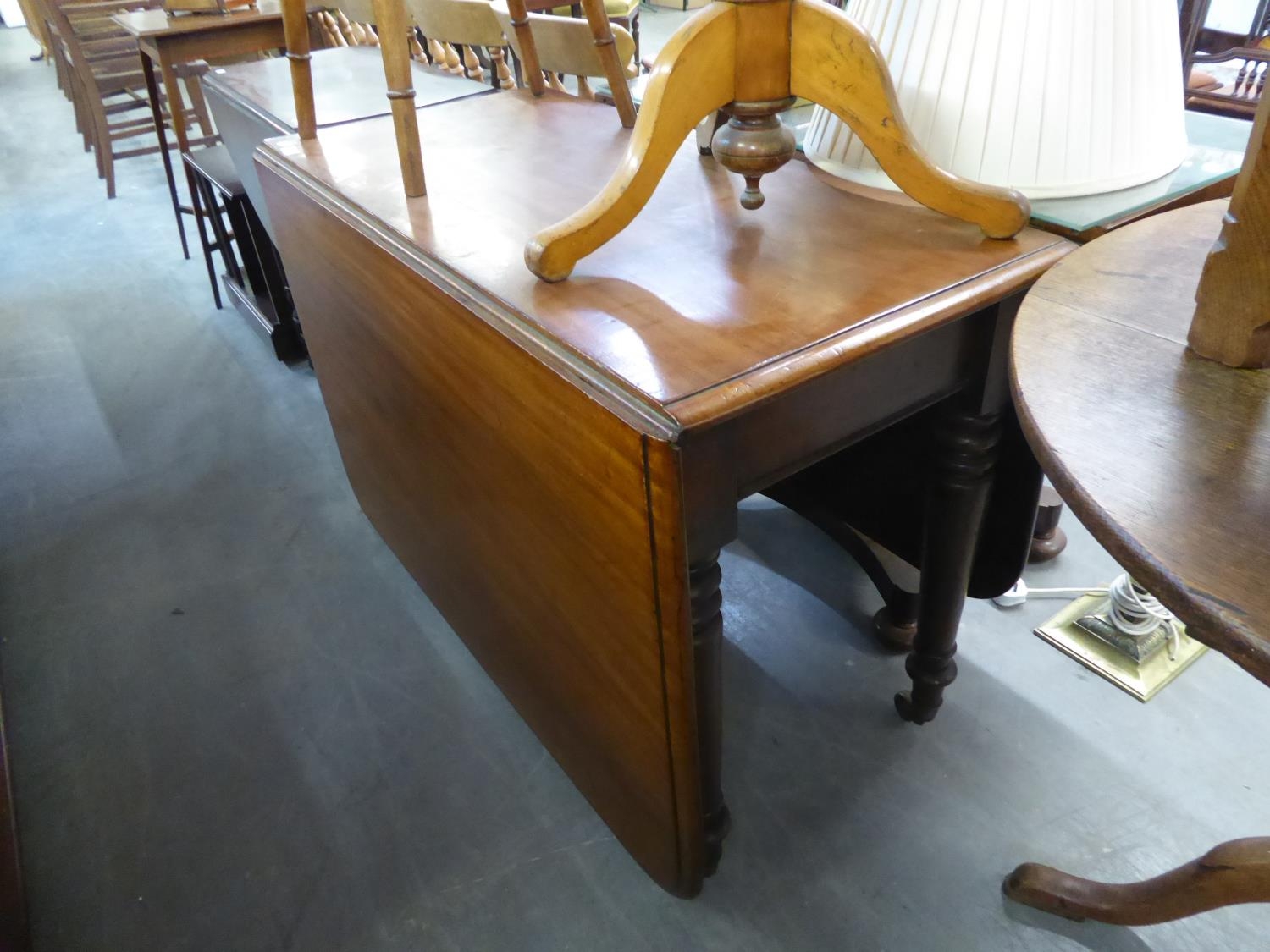 A VICTORIAN MAHOGANY DROP-FLAP DINING TABLE ON TURNED SUPPORTS