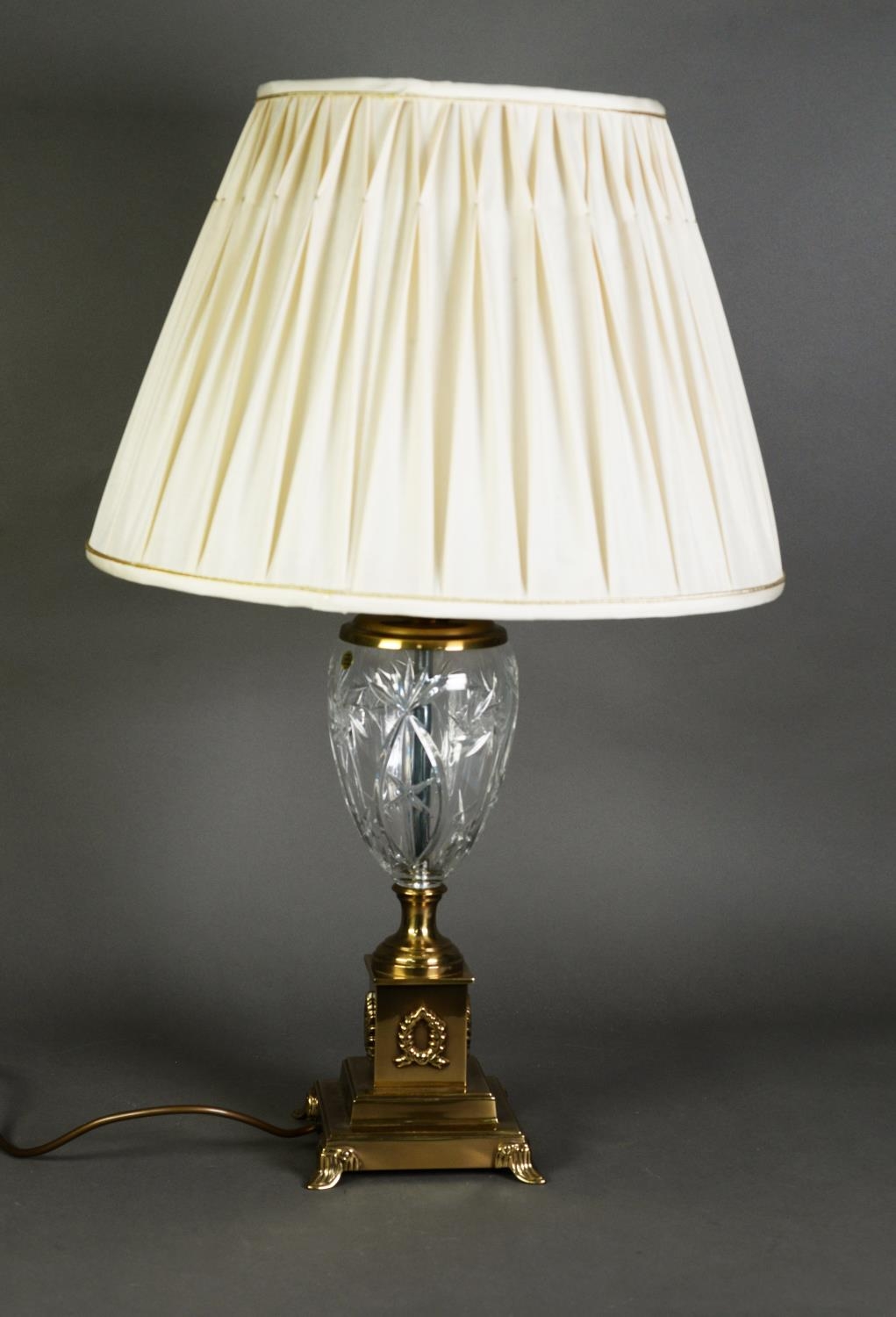 BRASS TABLE LAMP with cut glass urn shaped body, on brass foot and brass square, stepped plinth base