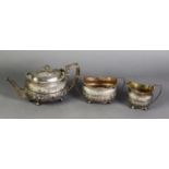 GEORGE III THREE PIECE EMBOSSED SILVER TEASET, of rounded oblong form with angular scroll handles,