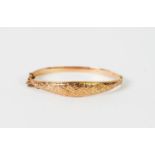 GEORGE V 9ct GOLD HINGE-OPENING HOLLOW BANGLE, the slightly domed tapering top foliate chased,