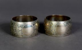 VICTORIAN PAIR OF ENGRAVED SILVER NAPKIN RINGS, of swollen form, decorated with leaves and vacant