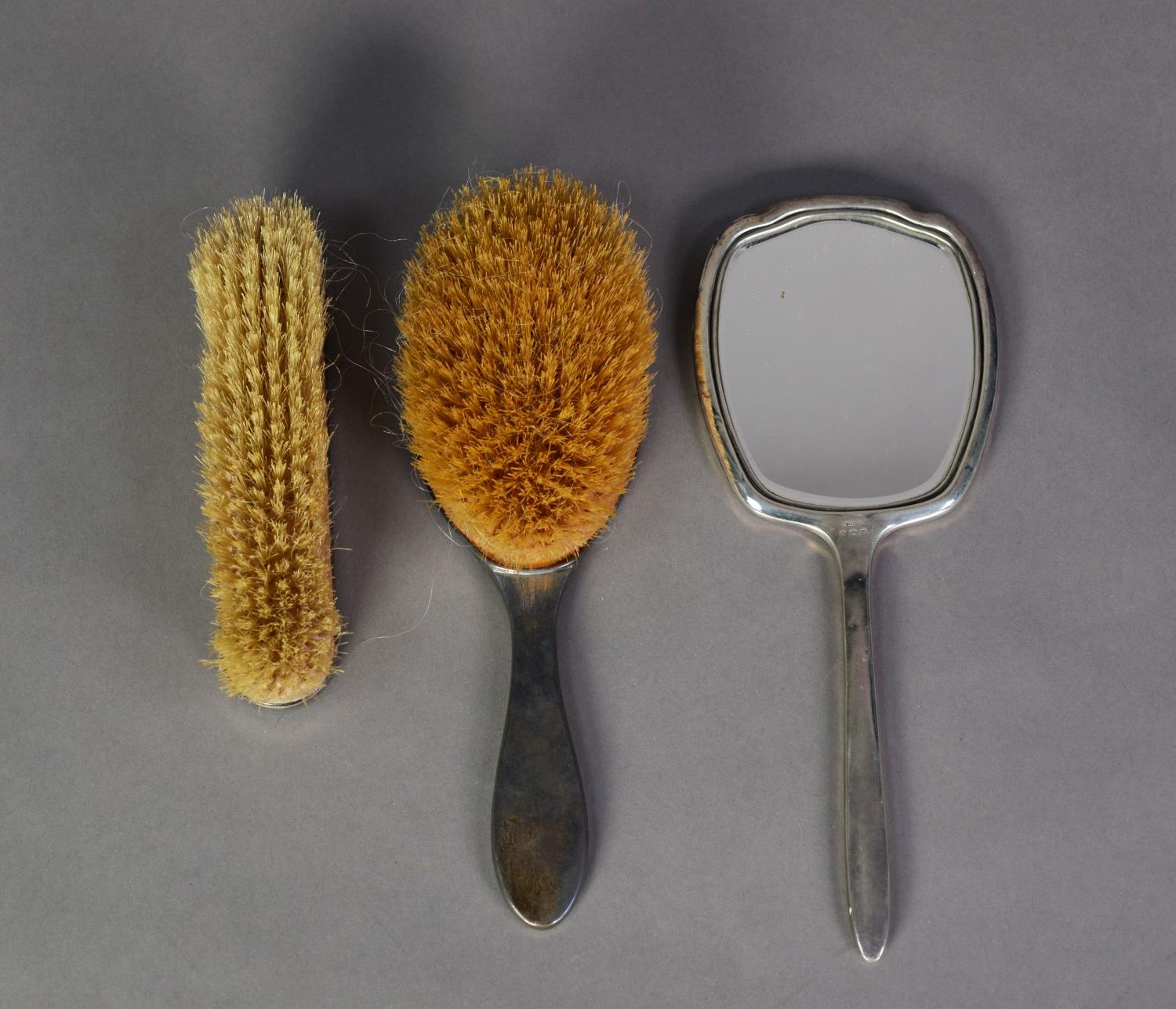 MATCHED THREE PIECE ENGINE TURNED SILVER BACKED DRESSING TABLE HAND MIRROR AND BRUSH SET, the