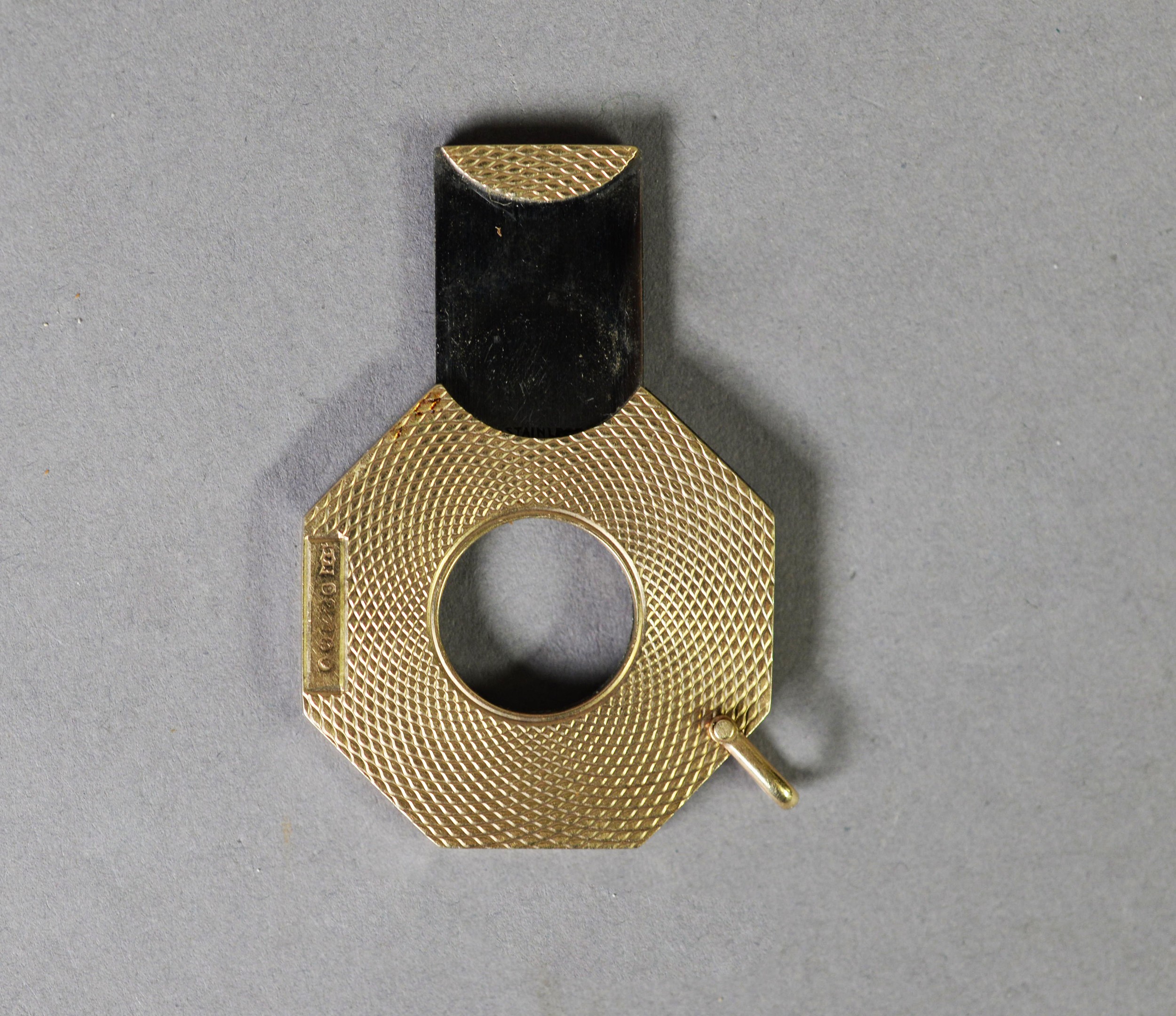 9ct GOLD ENGINE TURNED CIGAR CUTTER, ocatgon and flat, with suspension bale, 3.5cm wide,