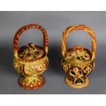 TWO SIMILAR TURKISH RED EARTHENWARE BASKET FORM COVERED STORAGE JARS, with applied simple floral