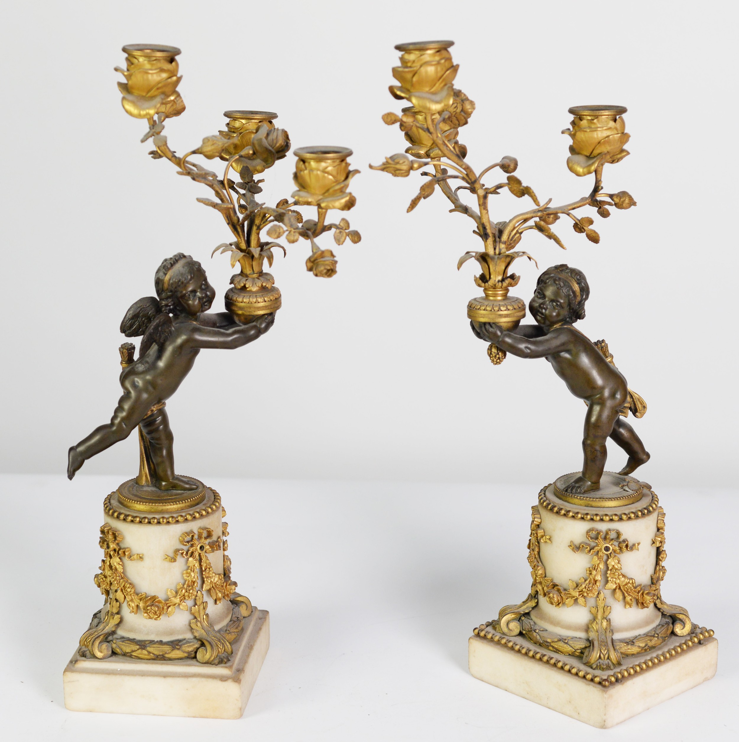A PAIR OF LATE 18TH CENTURY NEO-CLASSICAL PARCEL GILT BRONZE CANDELABRUM, modelled as winged putti