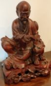 HEAVILY CARVED WOODEN ORIENTAL FIGURE OF A SEATED GENT WITH CAT ON STAND, APPROXIMATELY 33cm HIGH