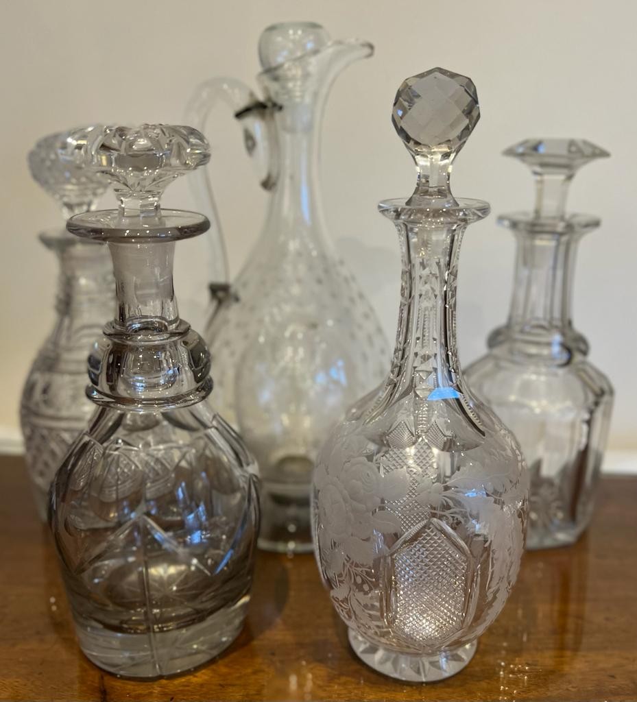 GLASS CLARET JUG AND FOUR VARIOUS DECANTERS JUG NEEDS REPAIRS AND SOME MINOR CHIPS ON DECANTERS