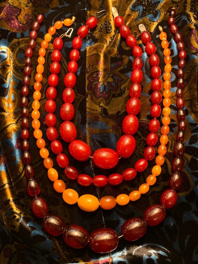 FOUR AMBER NECKLACES INCLUDING TWO RED, ONE BROWN AND ONE HONEY