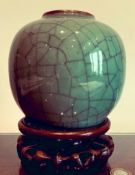 CELADON GREEN CRACKLE GLAZE OVOID VASE UPON A CARVED HARDWOOD STAND