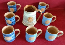 SEVEN VARIOUS GLAZED WOLD POTTERY CUPS, PLUS WOLD POTTERY TANKARD, ALL BEARING A UNITED NATIONS