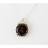 An 18ct yellow gold pendant set with a large round cut smokey quartz and diamonds, L. 2cm.