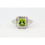 An art deco style 18ct white gold ring set with a centre princess cut bright peridot surrounded by