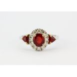 An 18ct white gold ring set with three bright rubies and brilliant cut diamonds, (N).