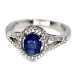 A 925 silver cluster ring set with an oval cut sapphire surrounded by white stones, (N).