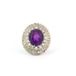 An 18ct yellow gold ring set with a large oval cut amethyst surrounded by two rows of diamonds, L.