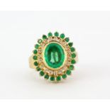 An 18ct yellow gold cluster ring set with a large oval cut natural emerald (approx. 3.30ct