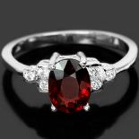 A 925 silver ring set with an oval cut garnet and white stones, (N).