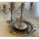 A pair of silver plated candelabra and three silver plated trays.