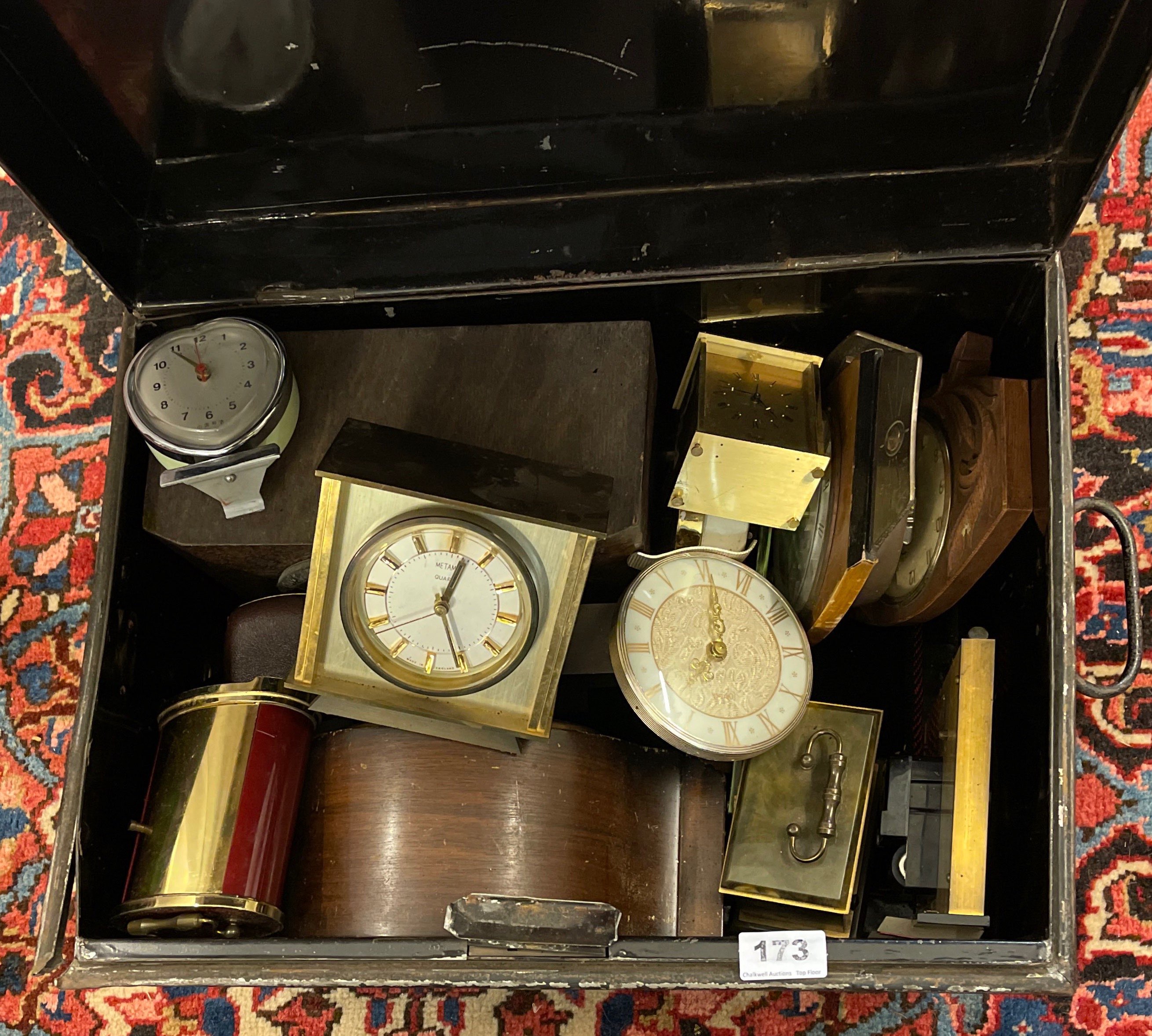 A tin trunk of mixed clocks.
