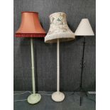 Two painted vintage wooden standard lamps with a wrought iron standard lamp.