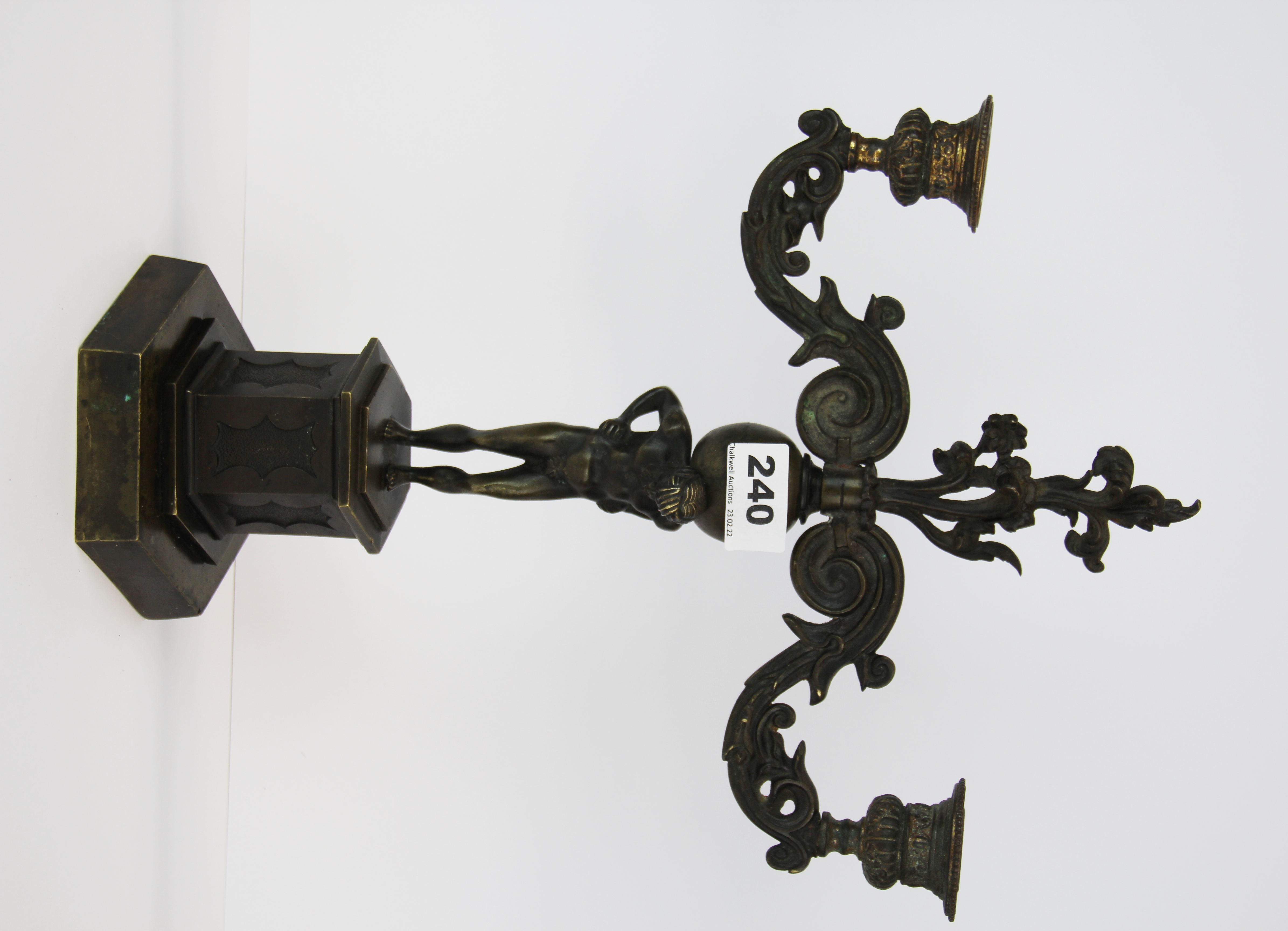 A 19th century bronze two branch candelabrum resting on Atlas, 38cm.