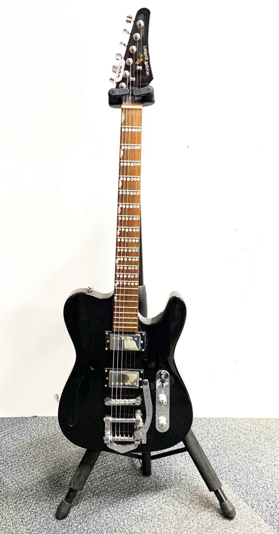 A black Thinline Telecaster style electric guitar with stand.