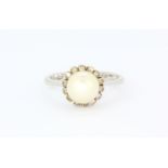 An 18ct white gold ring set with a cultured pearl surrounded by small diamonds, (M).