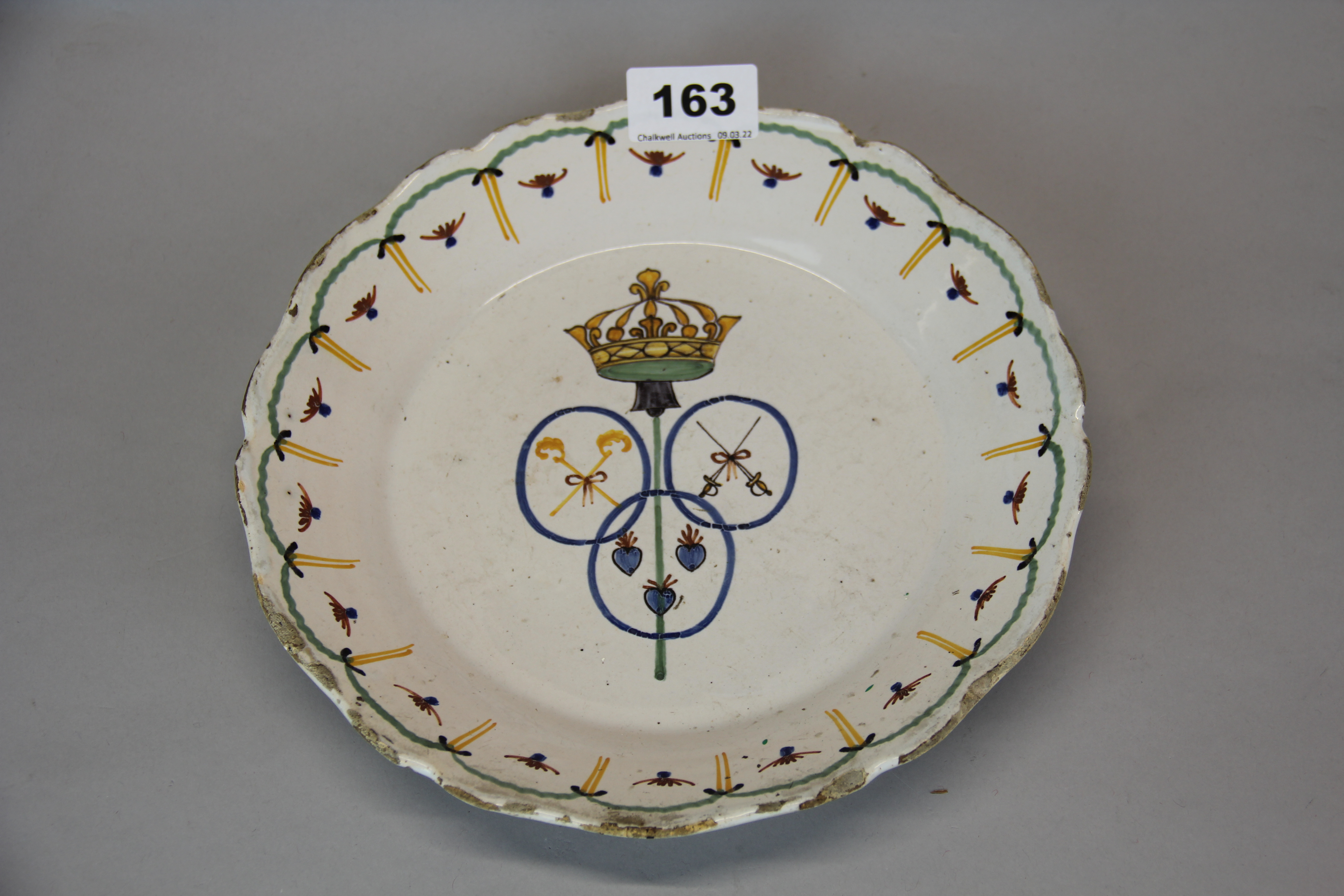 An 18th century French hand painted tin glazed pottery plate with armorial design to the centre,