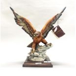 A resin figure of an eagle spreading its wings mounted on a wooden base, signed G. Armani, H.
