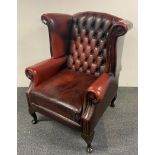 An oxblood leather wingback armchair.