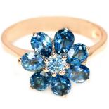 A 925 silver rose gold gilt flower shaped cluster ring set with oval cut London blue topaz, (I).