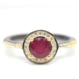 A 925 silver gold and rhodium plated halo ring, set with a round cut ruby surrounded by white