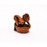 A signed carved erotic fruitwood netsuke of a young woman and a frog.
