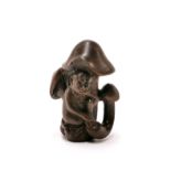 A carved fruitwood Netsuke of a monkey sitting beneath a mushroom with black obsidian eyes.