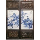 A pair of Chinese hand painted porcelain tiles, mounted in carved wooden frames, H. 85cm, W. 32cm.