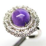 A 925 silver cluster ring set with a cbaochon cut amethyst surrounded by two rows of white