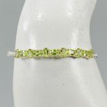 A 925 silver bangle set with oval cut peridots, L. 5.4cm.