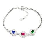 A 925 silver bracelet set with oval cut sapphire, ruby and emerald, surrounded by white stones, L.