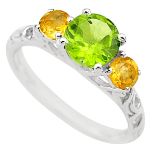 A 925 silver ring set with a round cut peridot flanked by citrines, (P.5).