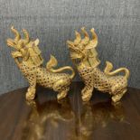 A pair of Thai carved wooden gilt and mirrored guardian lions, H. 45cm. Both slightly A/F.