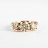 An 18ct rose gold (stamped 750) ring set with three brilliant cut fancy light brown diamonds, centre