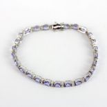 A white metal (tested 9ct gold) bracelet set with oval cut tanzanites and diamonds, L. 18cm.