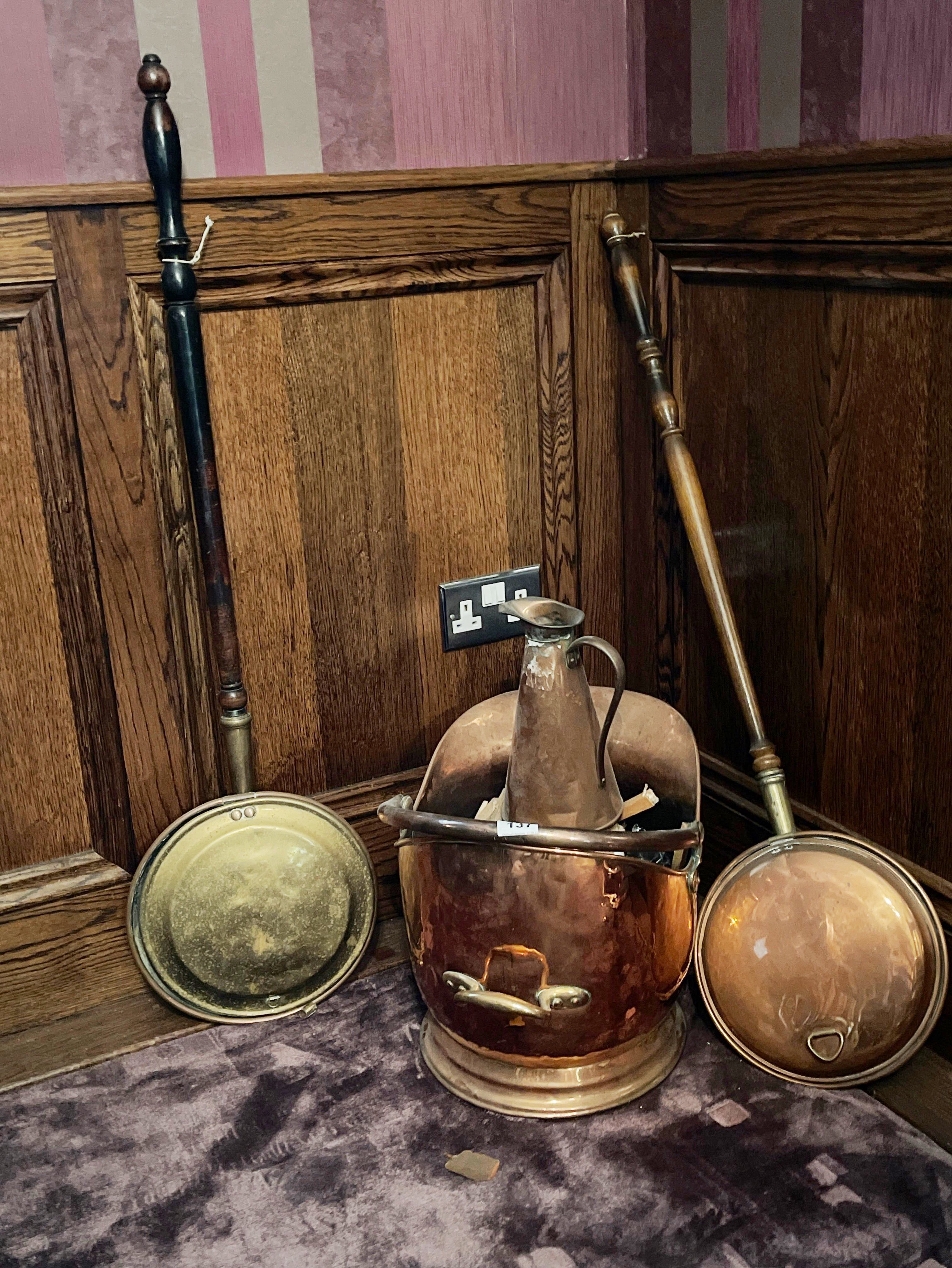 An antique copper coal skuttle with two warming pans and a copper jug.