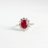 An 18ct white gold (stamped 750) cluster ring set with an oval cut ruby and brilliant cut