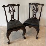 A pair of reproduction carved mahogany hall chairs with dropping button leather seats.