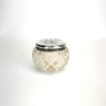 A small hallmarked silver topped cut crystal dressing table pot with impressed decoration of