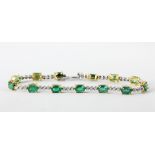 An 18ct yellow and white gold (stamped 750) bracelet set with oval cut emeralds and brilliant cut