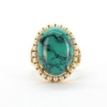An 18ct yellow gold (stamped 18k) cluster ring set with a large cabochon cut turquoise surrounded by